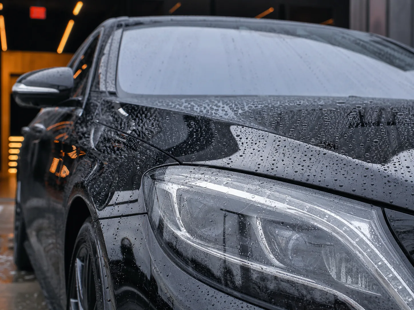 Water beading across a glossy ceramic-coated black vehicle