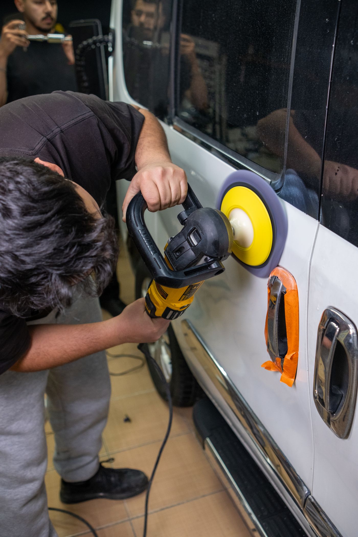 A detailer machine-polishing the exterior of a vehicle